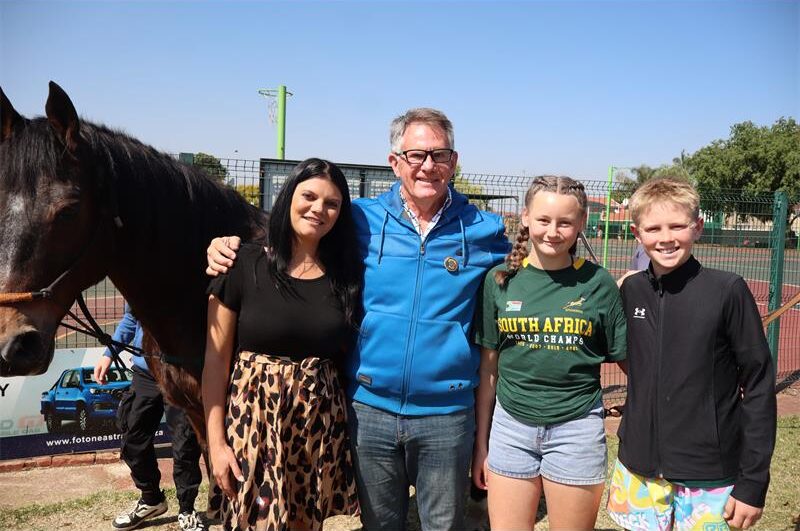 A lady wearing a leopard print dress, standing next to a man in a blue jacket, a girl wearing a green top and a boy wearing a black jacket.