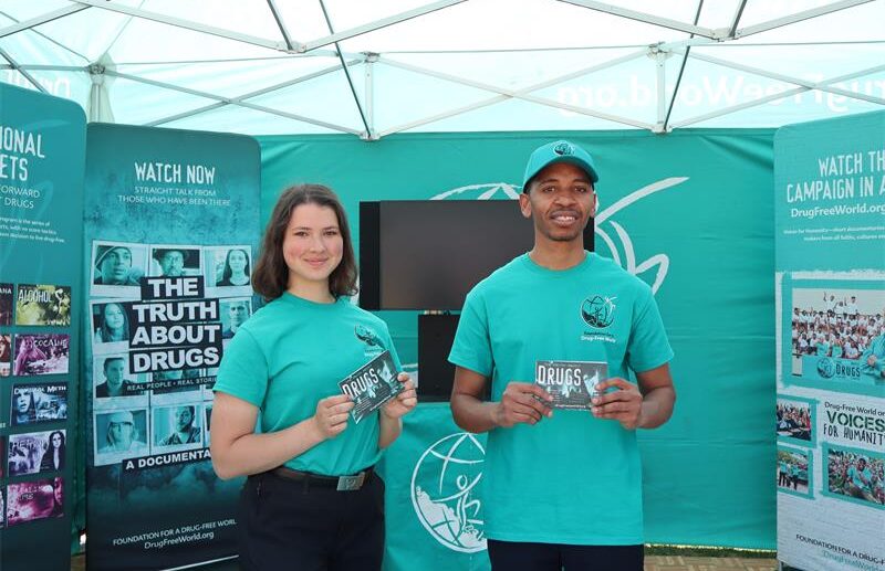 A white lady and a black man standing next to each other both wearing green tops