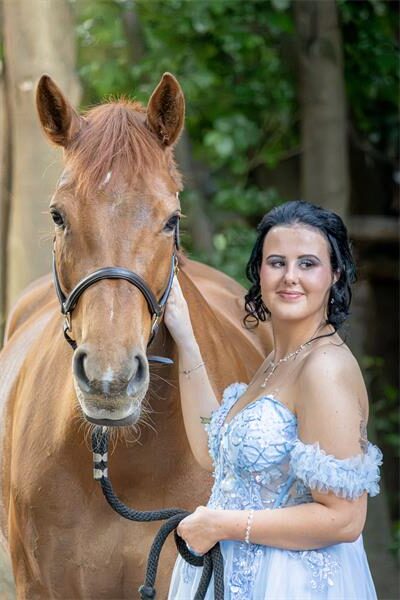 Girl in evening wear standing with a horse
