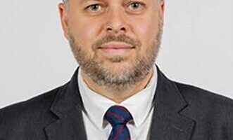 A man in a black suit and a blue tie.