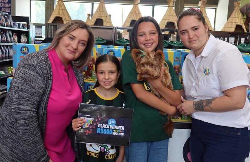 Two ladies standing next to show young girls, one girl is holding a dog.