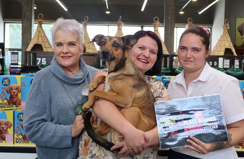 Three ladies standing next to each other one is holding a dog.