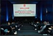 A cinema setting with the screen in the front and a title Why Blood Matters on the screen, with people in seats photographed from behind.