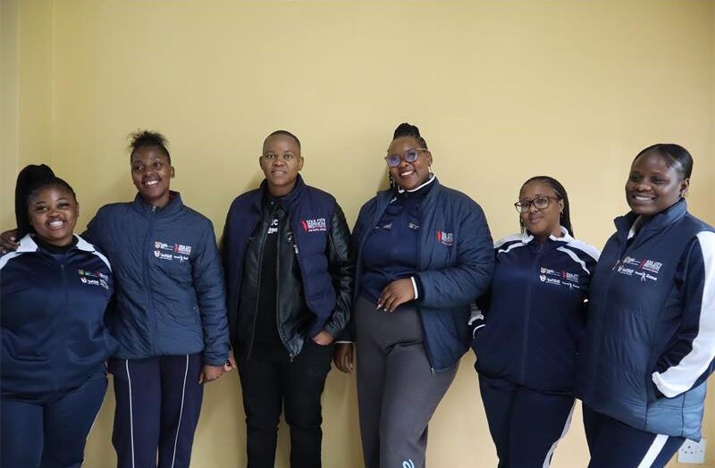Ladies standing in a row wearing navy blue jackets
