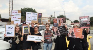 A group of people standing with placards outside a court building.