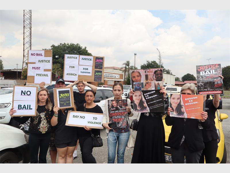 A group of people standing with placards outside a court building.