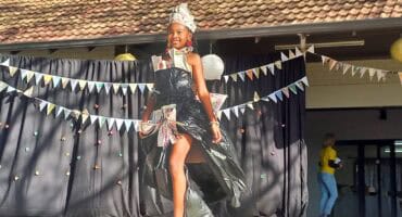 Black girl walking on a stage with a dress made of black bags