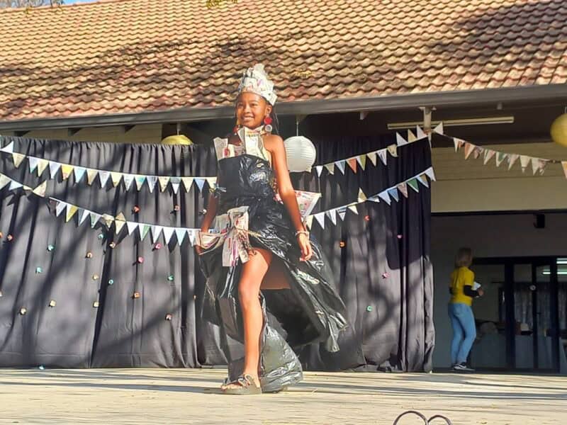 Black girl walking on a stage with a dress made of black bags