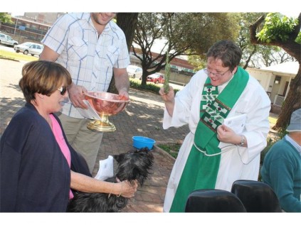 Diane van Niekerk (left) and her dog are blessed with holy water, by the priest, Debbie Wesseloo.