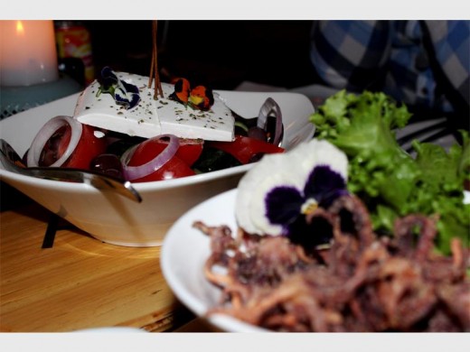 The Greek Salad, with a bowl of Crispy Salt and Pepper Squid Heads, served with honey aioli, in the foreground.