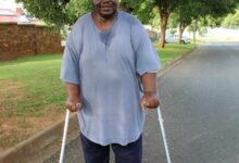 A black man with a blue shirt holding two crutches