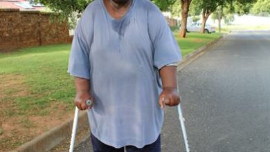 A black man with a blue shirt holding two crutches