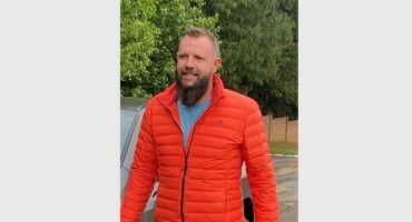 Man with a beard wearing an orange puffer jacket