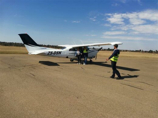 AEROPLANE Small aircraft on runway with three people in the image.