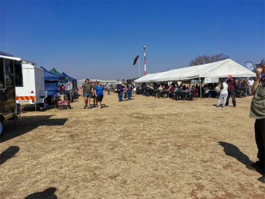 Market Tent, vehicles and people at an aviation and music festival.