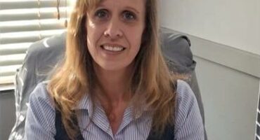 White woman sitting behind a desk