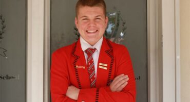Rugby player Clayton Kewley is pictured wearing a red blazer, white shirt and tie.