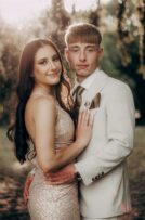 White girl wearing a tan coloured dress standing with a boy wearing a tan suit