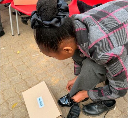 Photo of a young girl putting on new school shoes.