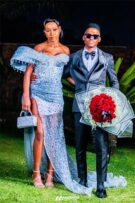 Balck girl waring a pale blue dress with a black boy wearing a grey suit, holding red flowers.