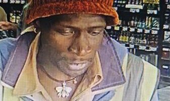 A black man wearing a red beaning, a reflective jacket and overalls