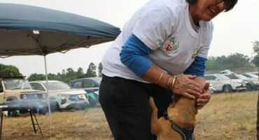Woman with short dark hair petting a dog.