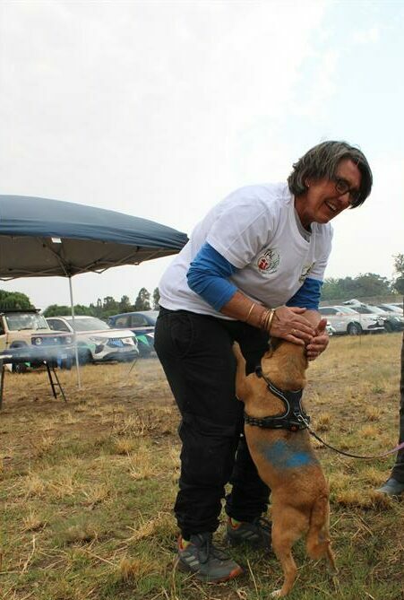 Woman with short dark hair petting a dog.