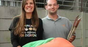 Woman with long dark hair with a man wearing a grey shirt.
