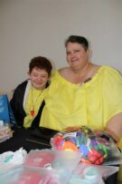 Woman and girl, with red hair, both wearing matching yellow dresses.