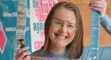 Woman with blue glasses holding a piece of hair and a photo board