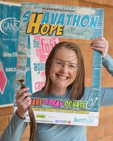 Woman with blue glasses holding a piece of hair and a photo board