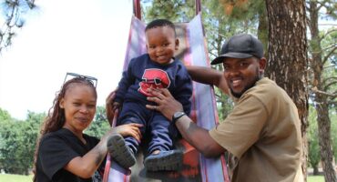 Black woman and man with a boy on a red slide