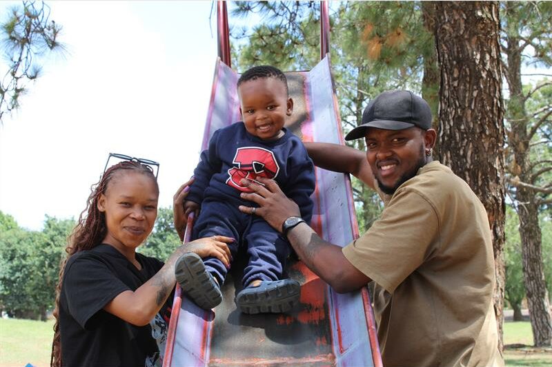Black woman and man with a boy on a red slide