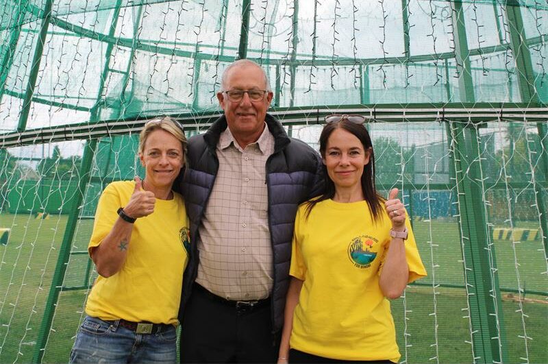 Two women and a man standing in front of green mesh.