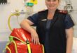 Nurse standing in hospital room with her arm resting on a bag.