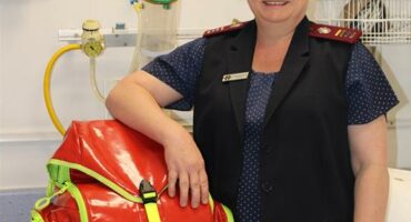 Nurse standing in hospital room with her arm resting on a bag.
