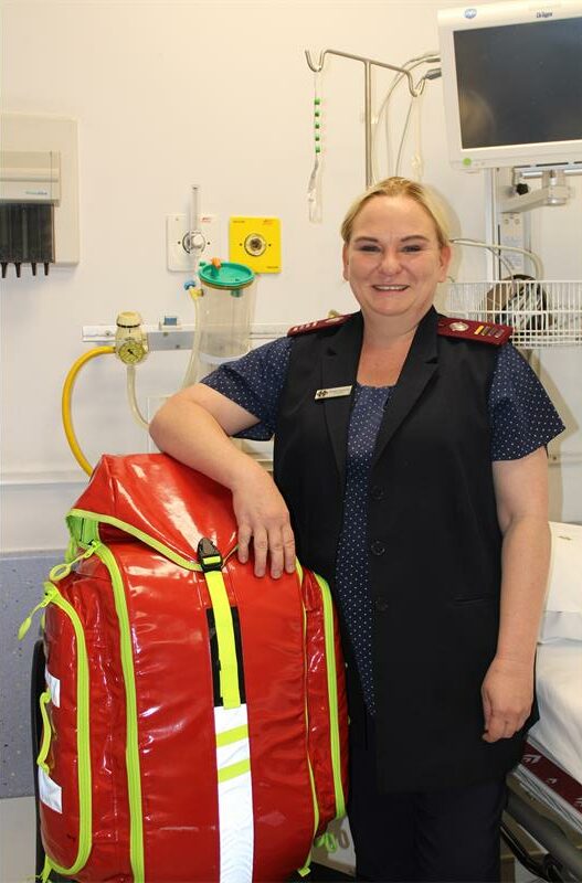 Nurse standing in hospital room with her arm resting on a bag.