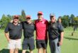 A group of four men standing on a putting green