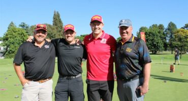 A group of four men standing on a putting green