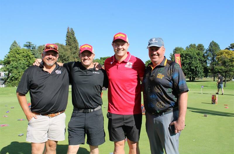 A group of four men standing on a putting green
