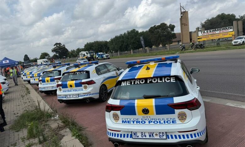 A group of police officers and a fleet of police vehicles parked next to each other on a public road