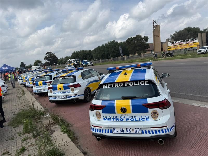 A group of police officers and a fleet of police vehicles parked next to each other on a public road