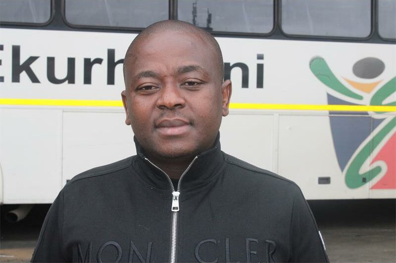 MMC of Roads and Transport Management, Andile Mngwevu, with a white municipal bus in the background.