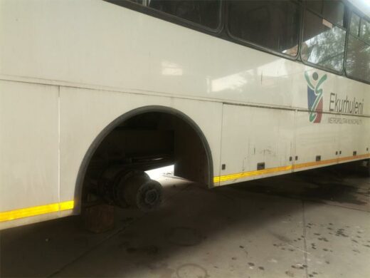 A white Ekurhuleni metro bus standing on bricks.