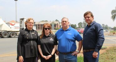 Four people, two men and two women standing next to the side of the road.