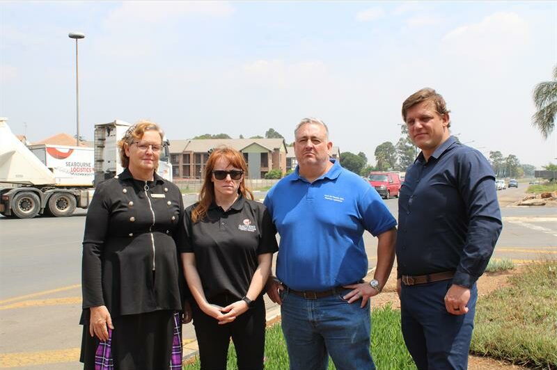 Four people, two men and two women standing next to the side of the road.