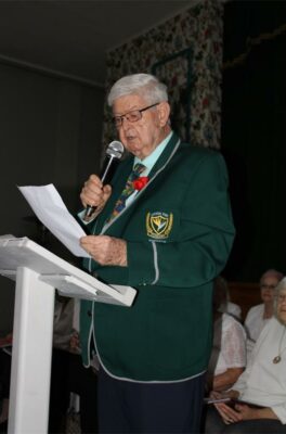 A grey-haired man reading from a piece of paper.