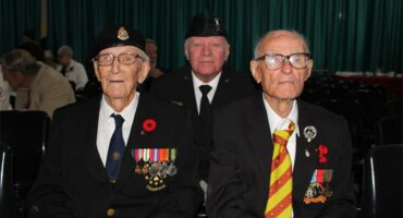 Three elderly men wearing WWII medals.