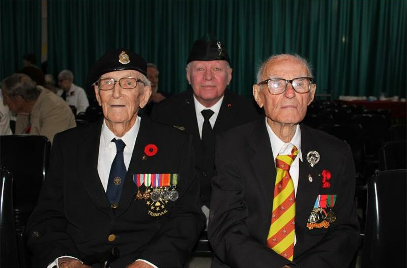 Three elderly men wearing WWII medals.
