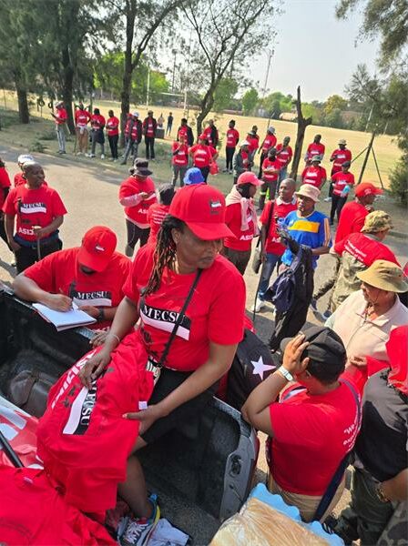 A group of protesters in red union t-shirts marching outside offices.